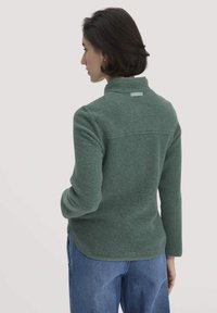 Donkergroene fleece pullover met een hoge kraag, met een gladde textuur, een getailleerde pasvorm en een subtiele logo-tag op de achterkant.