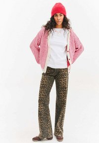 Červená pletená čepice, přehnaně velký růžovo-bílý pruhovaný kardigan, bílé tričko a kalhoty s leopardím vzorem. Vzhled doplňují hnědé mokasíny.