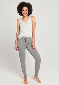 Ljusgrå linne med spetsdetaljer, parat med grå sweatpants med dragsko i midjan och knapppdetaljer, vilket framhäver en avslappnad stil.