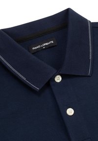 Granatowa koszulka polo z teksturowanej tkaniny, z kołnierzykiem z białym przeszyciem i zapięciem na guziki z dwoma jasnymi guzikami.