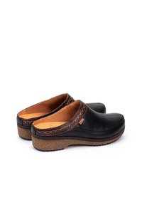 Sabots en cuir noir avec un bout arrondi, des détails en cuir marron cousus le long de l'ouverture, et une semelle texturée semblable au liège pour une meilleure adhérence.