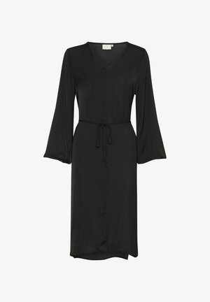 Juoda suknelė, V formos iškirptė, platėjantys ilgomis rankovėmis, raišteliu reguliuojama juosmuo, iki kelių ilgio, lygus paviršius, lengvas audinys. Be raštų ar akcentų.