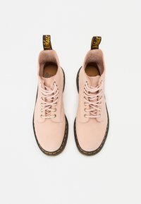 Rosa ruskind lace-up ankelsko med rund tå, sort sål med gul syning og en løkke tag bagpå.