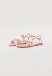 Pink sandals with studded details, open-toe design, and ankle straps. Soft material and flat soles for comfortable wear.