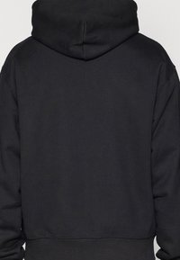 Black hooded sweatshirt, made of soft fabric, features a seamless design with ribbed cuffs and a relaxed fit. No visible logos or patterns.