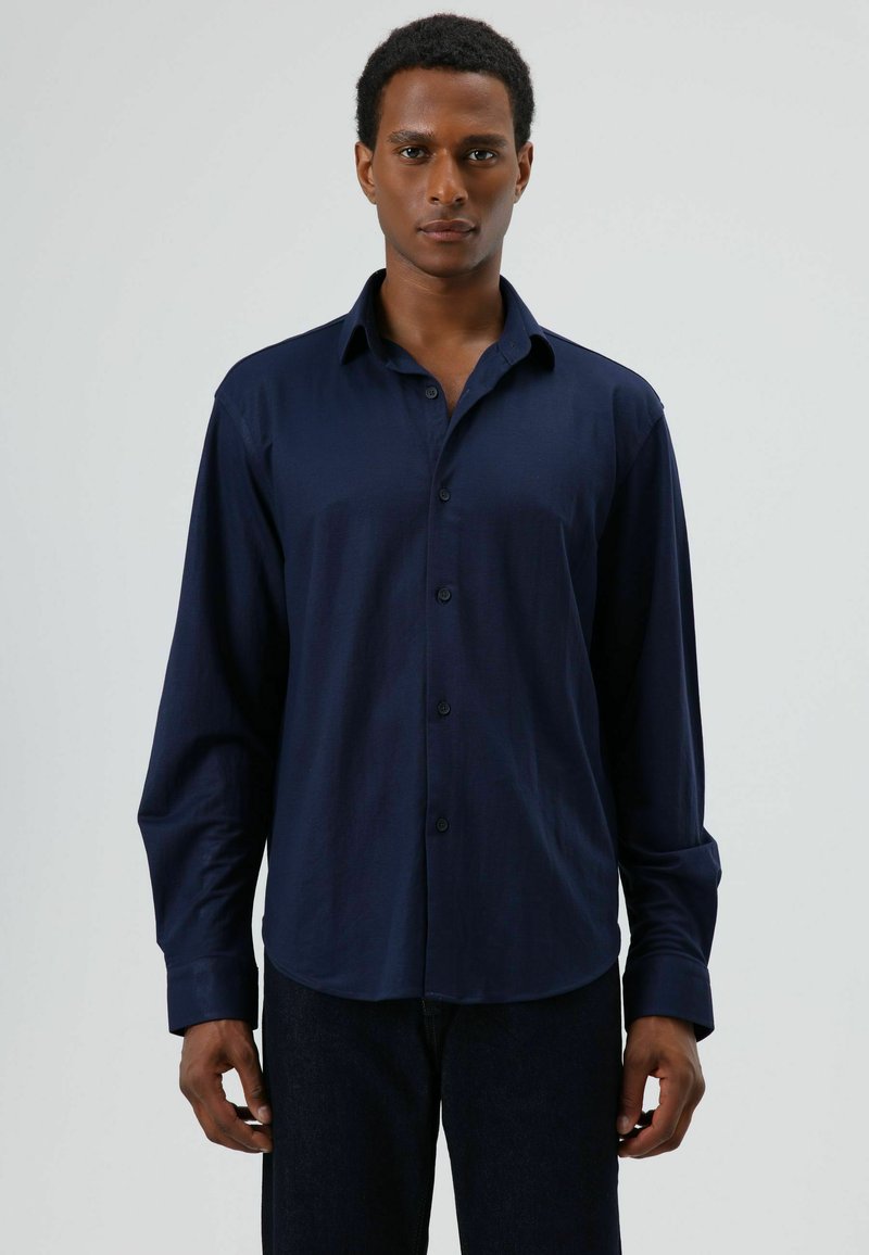 Navyblauw overhemd met knopen, gemaakt van gladde stof, voorzien van een klassieke kraag, lange mouwen en een afgeronde zoom. Simpel ontwerp zonder patronen.