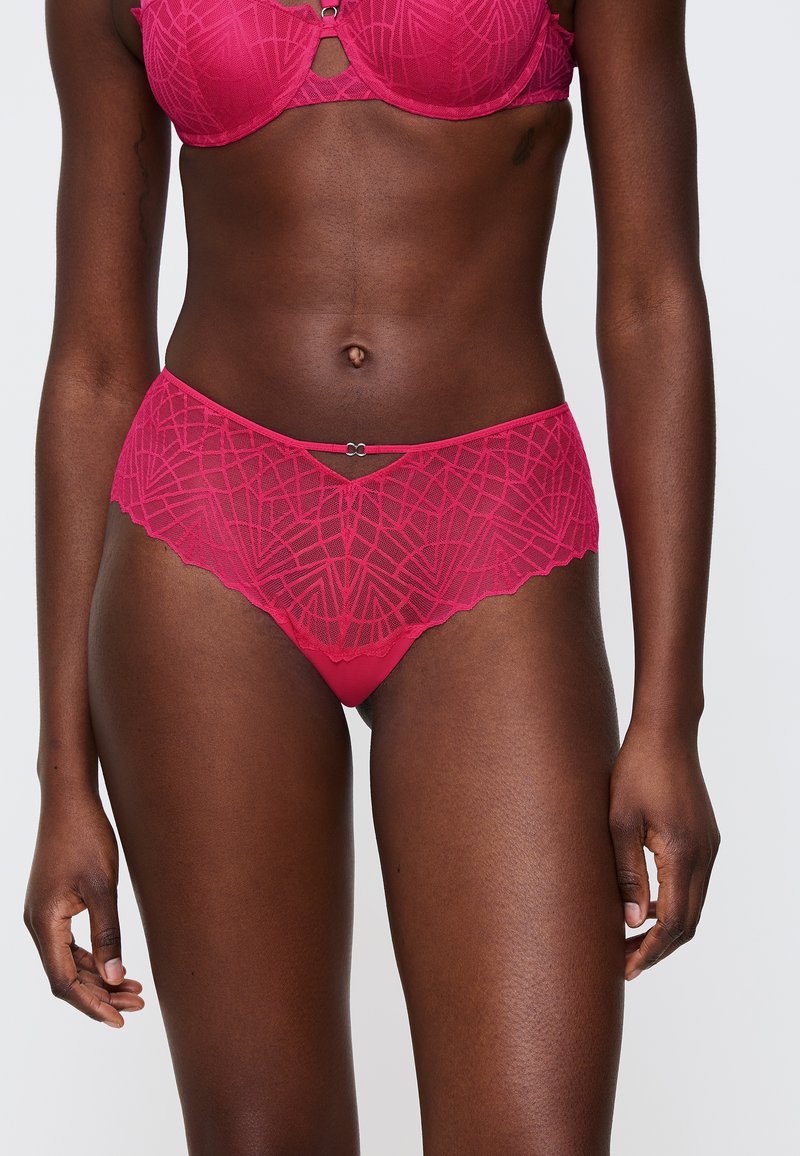 Fuksjowy komplet bielizny koronkowej z geometrycznymi wzorami, falbaniastymi krawędziami oraz dekoracyjnym akcentem metalowym. Gładka tekstura, dopasowany krój.