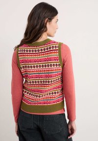 Pleteni pulover bez rukava s višebojnim uzorkom na leđima u nijansama ružičaste, crvene i zelene. Dugi ružičasti rukavi s okruglim izrezom.