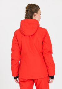 Rote wasserfeste Jacke mit Kapuze, die eine glatte Textur und elastische Bündchen aufweist. Das Design ist körperbetont und betont eine schlanke Silhouette.