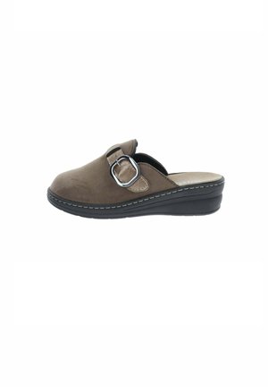 Zueco marrón sin cordones, con una correa ajustable con hebilla, forro beige y suela negra gruesa, mostrado de lado sobre un fondo blanco.