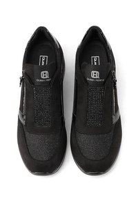 Zapatos negros sin cordones que presentan una combinación de ante y tela texturizada, con cremalleras decorativas y un interior acolchado para mayor comodidad.