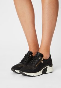 Svarta sneakers med en blandning av texturerade material, snörningsdesign, sidodragkedjedetalj och en kontrasterande vit och svart sula.