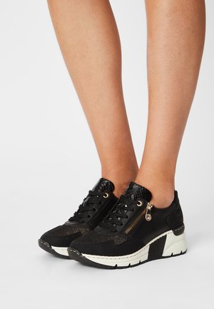 Svarta sneakers med en blandning av texturerade material, snörningsdesign, sidodragkedjedetalj och en kontrasterande vit och svart sula.