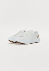 White athletic shoes with a smooth synthetic upper, lace-up design, and a brown rubber sole. Features a gold logo and stitching details.