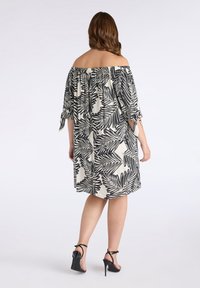 Vestido off-the-shoulder con un patrón de hojas de palma en blanco y negro, con un corte holgado, mangas de longitud hasta el codo y detalles atados.