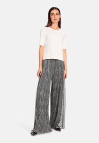 White short-sleeve top paired with black and white striped wide-leg pants. Outfit features a relaxed fit and smooth textures with a subtle sheen.