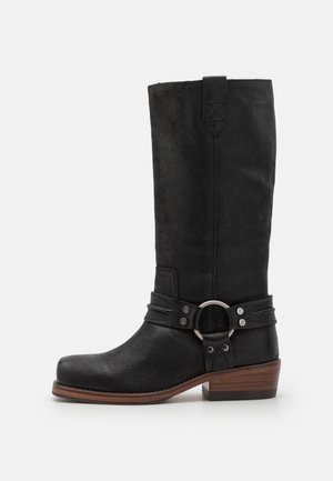 Schwarze Leder-Cowboy-Stiefel mit glatter Oberfläche, kniehoch, und einem dekorativen Riemen mit silbernen Ring- und Schnallenakzenten.