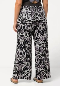 Zwart-witte wijde broek met abstract bloemenpatroon, elastische taille en zijzakken. Textuurstof met contrasterende zijpaneeldetails.
