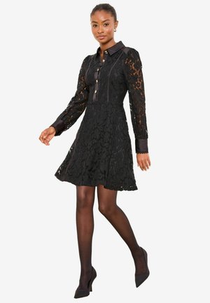 Schwarzes Spitzenkleid mit langen Ärmeln und durchgeknöpftem Vorderteil, das einen taillierten Oberkörper, einen ausgestellten Rock sowie kontrastierende Satin-Kragen und Manschetten aufweist.