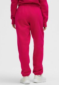Fuchsia joggers med elastisk midja och avslut. Tillverkade av mjukt tyg, med en avslappnad passform och matchade med vita sneakers.