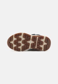 Baskets pour hommes avec une semelle en caoutchouc offrant une adhérence texturée, un dessus noir et des accents marron contrastants. Talon renforcé pour un soutien optimal.
