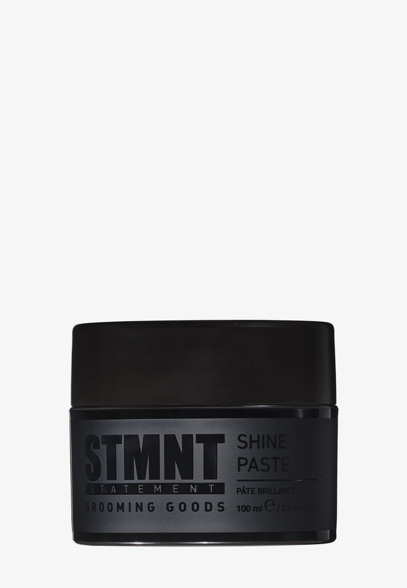 Zwarte pot van STMTNT Shine Paste, met een matte afwerking, vetgedrukte tekst en een draaideksel. Inhoud: 100 ml. Eenvoudig, functioneel ontwerp.