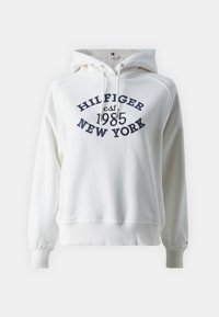 Felpa bianca con cappuccio regolabile, polsini e fondo a coste. Presenta la scritta blu "HILFIGER est. 1985 NEW YORK" sul davanti. Tessuto morbido.