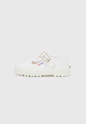 Chaussure Mary Jane en toile blanche avec semelle épaisse à crampons et boucle argentée, estampillée d'une petite étiquette "Superga" sur le côté.