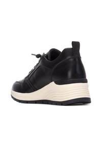 Zapatilla de cuero negro con un diseño texturizado, punta redondeada, cordones en la parte delantera y una suela blanca ligeramente elevada con surcos.