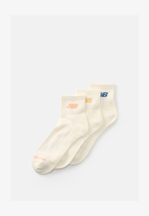 Trois paires de chaussettes de cheville couleur crème avec des bords côtelés, chacune arborant un logo "NB" de couleur différente en rose, jaune et bleu.