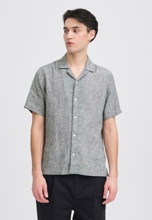 Kurzärmeliges graues Leinenhemd mit Kragen, mit einer durchgehenden Knopfleiste und einer strukturierten Oberfläche, kombiniert mit einer schwarzen Hose.