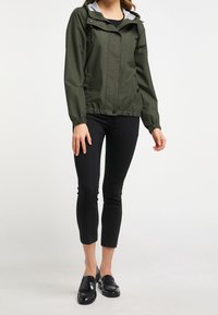 Jasnozielona, lekka kurtka z szarym kapturem, elastycznymi mankietami i zamkiem z przodu. W zestawie z czarnymi spodniami 3/4 i czarnymi loafersami.