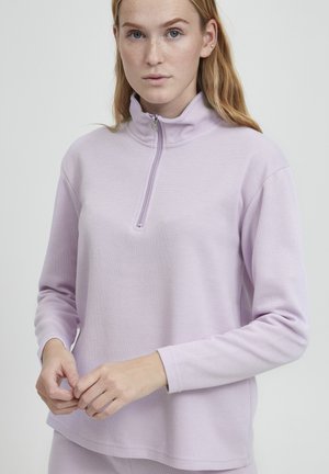 Helles Lavendel-Pullover aus weichem Material, mit einem Halbzip-Kragen und langen Ärmeln in lockerer Passform. Minimale Nähdetails.