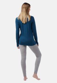 Long-sleeve teal top paired with light grey leggings. Top has a smooth texture and rounded hem; leggings are fitted with a soft, heathered pattern.