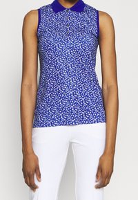 Ärmlös blå blus med krage, prydd med ett blommönster i vitt och ljusblått. Slät textur, åtsittande design och knäppning fram.