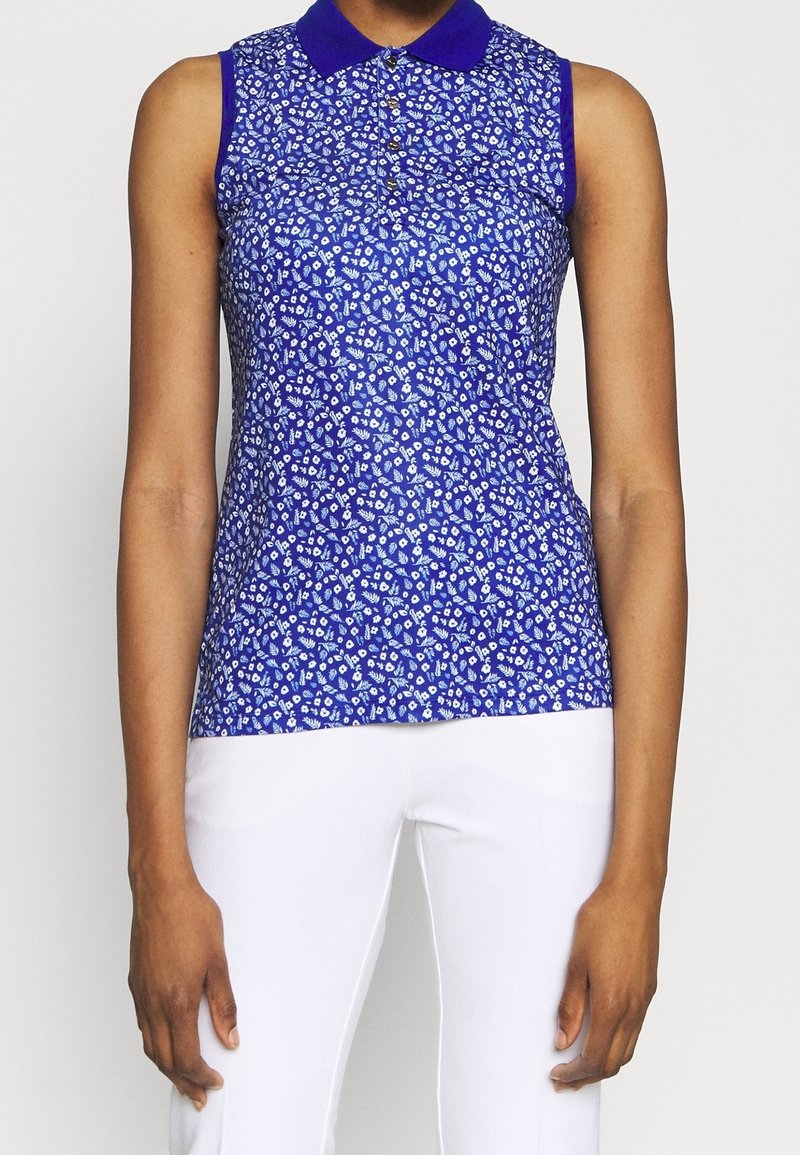 Ärmlös blå blus med krage, prydd med ett blommönster i vitt och ljusblått. Slät textur, åtsittande design och knäppning fram.