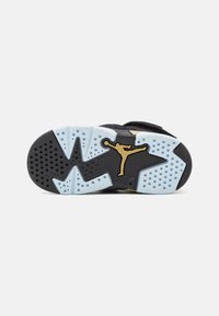 Črna podplat športnih copat z modrimi poudarki in zlatim logotipom Jumpman. Edinstven vzorec za oprijem s pikčastimi in valovitimi oblikami. Trajen gumijast material.