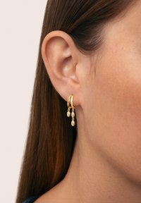 Orecchini a cerchio d'oro con due gemme chiare a forma di marquise pendenti e una fila di piccole gemme sul cerchio. Finitura in metallo liscia.