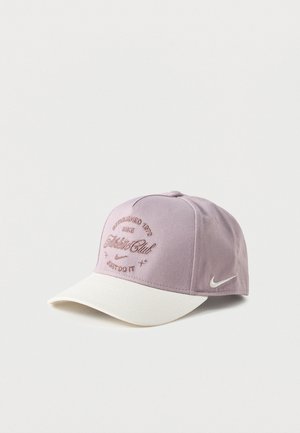 Casquette de baseball Nike violet clair avec visière blanche, texte brodé "Athletic Club", logo Nike swoosh et slogan "Just Do It" à l'avant.