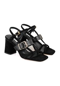Zwarte hoge hak sandalen van suede en leer, vierkante tenen, chunky blokhak en decoratieve gesp-accenten op de banden.