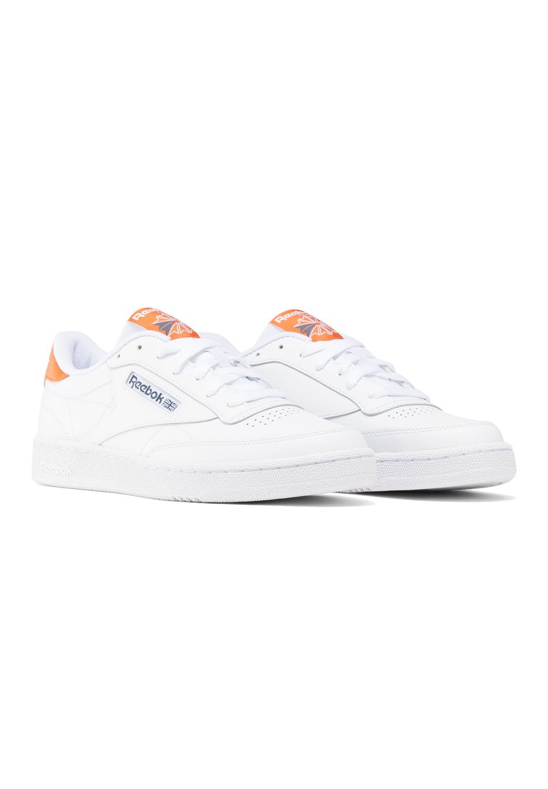 Zapatillas de cuero blancas con acentos en naranja, que cuentan con cordones redondos, capellada perforada y suela de goma texturizada. Logo detallado en el lateral y en la lengüeta.