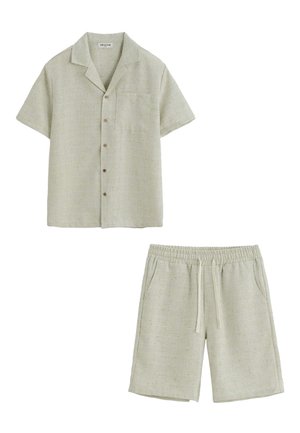Chemise beige à manches courtes avec boutons, col et poche poitrine, associée à un short beige à taille élastique avec cordon.