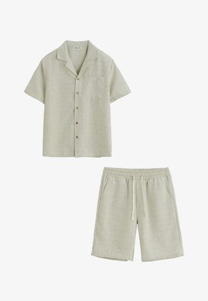 Chemise beige à manches courtes avec boutons, col et poche poitrine, associée à un short beige à taille élastique avec cordon.