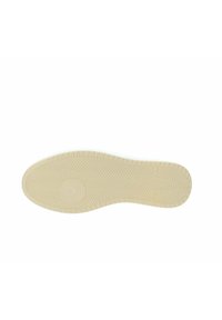Suola della scarpa con superficie in gomma beige testurizzata, caratterizzata da un motivo a zig-zag per la trazione e un logo circolare al centro.