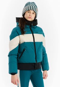 Teal bunda s páperím so smotanovými a čiernymi vodorovnými pruhmi, zipsom, bočnými vreckami a priliehavým čiernym lemom. V kombinácii so vzorovanou čiapkou.