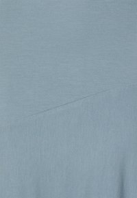 Tecido azul claro com uma textura suave e um detalhe de costura diagonal, criando uma forma geométrica na superfície.