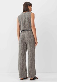 Zwart-wit geblokte jumpsuit met een mouwloos ontwerp, een broek met een brede pijp, een ceintuur in de taille en een gladde stoftextuur.
