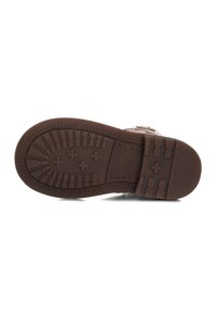 Brown rubber shoe sole with textured tread pattern, featuring grooves and ridges for traction. The heel is slightly raised.