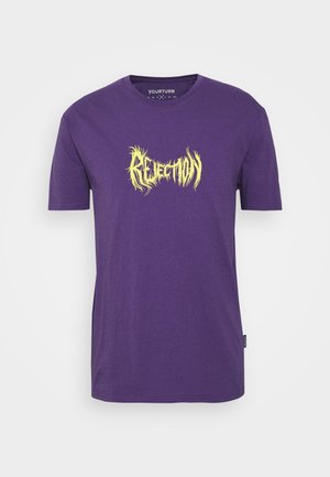 T-shirt violet à manches courtes avec le texte stylisé jaune « REJECTION » centré sur la poitrine, col rond et petite étiquette noire sur la couture latérale.