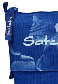Blaue Stofftasche mit strukturiertem Design, versehen mit einem auffälligen weißen Logo "Satch" und einem blauen Reißverschluss. Glattes, leichtes Material.